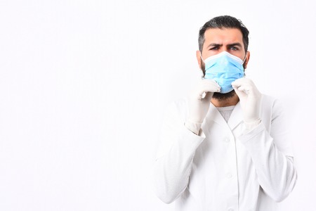 Bearded man, long beard. Brutal caucasian doctor or unshaven hipster, postgraduate student in medical gown and gloves wearing mask isolated on white studio background. Medicine conceptの写真素材