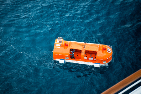 Cozumel. Mexico-November 19, 2016: Orange rescue or lifeboat, modern boats, for emergency evacuation loading for safety training from ship with people on blue sea backgroundのeditorial素材