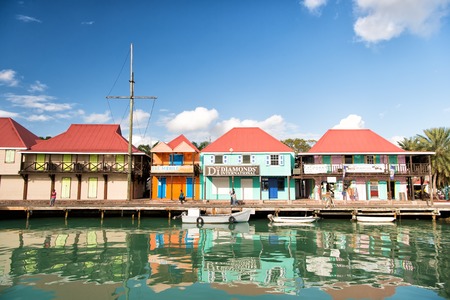St. John, Antigua - March 05, 2016: cute houses at harbor with people, yacht, boat, ship...