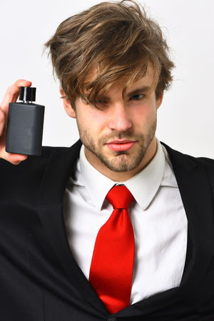 Bearded man, short beard. Caucasian stylish business man with moustache in elegant black suit and red tie posing with perfume in studio isolated on white backgroundの写真素材