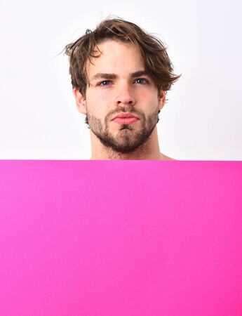 Bearded man, short beard. Caucasian sexy young macho with stylish hair and moustache on serious face holding fuchsia or pink paper sheet isolated on white studio background, copy spaceの写真素材