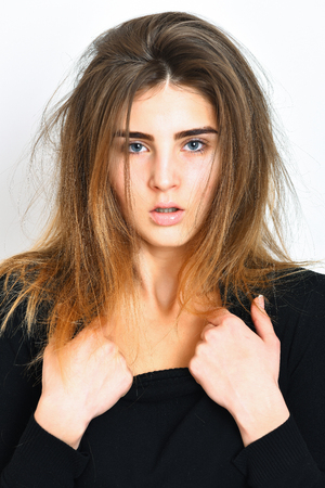 pretty cute sexy brunette girl or caucasian woman with ruffled hair posing in black sweater on white studio backgroundの写真素材