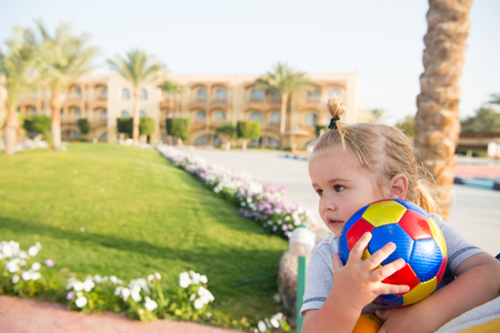 cute child or small baby boy playing with colorful ball at sunny summer outdoor with green grass. kid has cute face and blonde hair on natural background. sport and vacation. childhood and happinessの写真素材