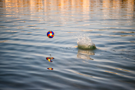 colorful toy ball, football game attribute bounce off blue wavy water. summer outdoor sport. leisure...