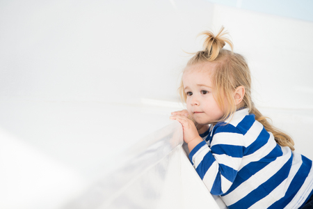 fashionable small baby boy or cute child model in stripped marine shirt and stylish blonde hair on yacht on white background, copy space. kid nautical fashionの写真素材