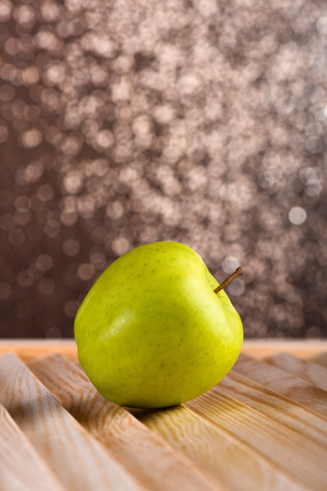 fresh green apple on brown wooden table, sparkling studio background, side view, selective focus, copy spaceの写真素材