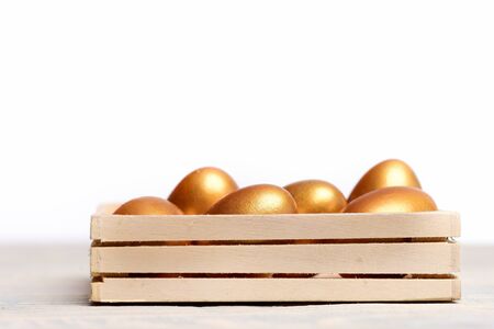 golden eggs, traditional easter food painted in gold metallic color in wooden box isolated on white background, future life, luxury and success, business and finance, retirement, copy spaceの写真素材