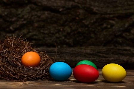 colorful eggs inside nest on brown vintage wooden background. Happy Easter concept, side viewの写真素材