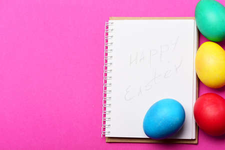 colorful painted eggs, paper notebook on pink background, happy easter, cooking and eating, recipe and menu design, healthy food, farming and agriculture, drawing and art, copy spaceの写真素材