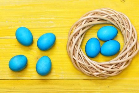 set of traditional eggs painted in blue color inside woven wooden wreath on yellow vintage background. Happy Easter conceptの写真素材