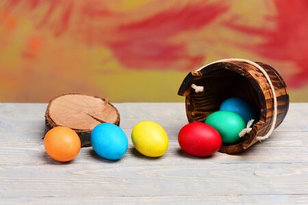 tree stump near wooden bucket or pail with colorful painted handmade eggs, happy easter concept,...