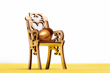 wooden chair with golden egg in broken shell, easter food painted in gold metallic color on yellow wood isolated on white background, healthy food, eating and cooking, luxury and success, copy spaceの写真素材