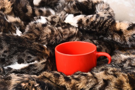 Red orange tea or coffee cup or ceramic mug for drink on spotted fluffy fur coat background, closeupの写真素材