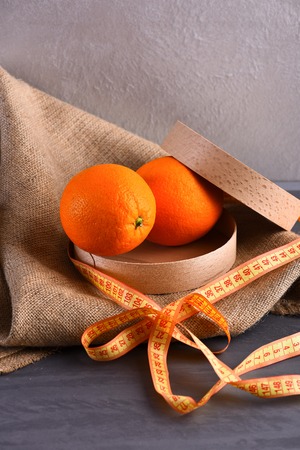 oranges in wooden box with measuring tape on sackcloth napkin, studio wall background, side viewの写真素材