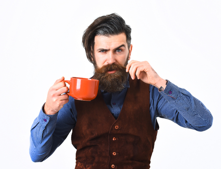 bearded man, long beard, brutal caucasian hipster with moustache holding mug or cup with coffee, tea with serious face isolated on white backgroundの写真素材