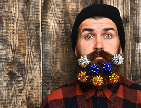 Bearded man, long beard. Brutal caucasian surprised hipster with colorful gift decoration stars in...