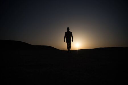 muscular man silhouette on sunset fiery sky background in mountain, sport and recreation, future and...