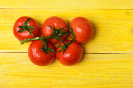 tomatoes on vine, ripe natural and organic on yellow vintage wooden background. Market fresh vegetable conceptの写真素材