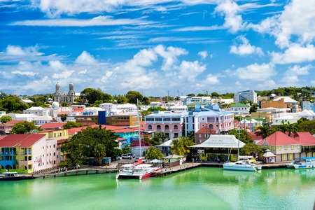 St. John, Antigua - March 05, 2016: cute houses at harbor with yacht, boat, ship transportation in bay with sea, ocean water, blue cloudy sky sunny summer on natural background. traveling and vacationのeditorial素材
