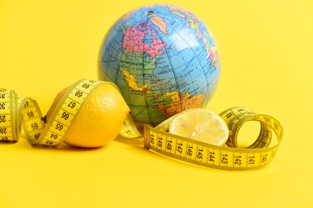 globe and lemon with measuring tape on yellow background. Diet and health in world conceptの写真素材