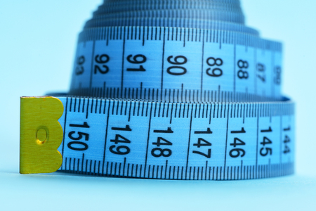 Knot of blue measure tape, neatly placed isolated on light blue background, close upの写真素材