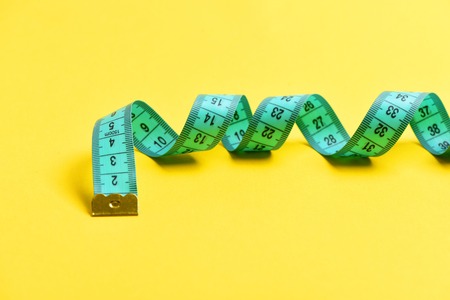 measuring tape for tailor on yellow background, close upの写真素材