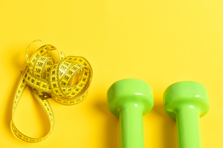 dumbbells with centimeter on yellow background. Exercise and fitness conceptの写真素材