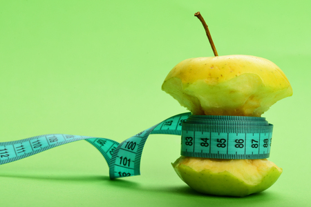 Concept of healthy food: apple tied by blue measure tape on light green backgroundの写真素材