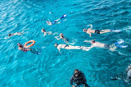 Hurghada, Egypt - February 24, 2017: group of people, adults and children, with diving masks and snorkels swimming underwater on sunny day in blue sea or ocean water. Idyllic summer vacationのeditorial素材