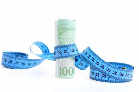 roll of euro money with measuring tape isolated on white backgroundの写真素材