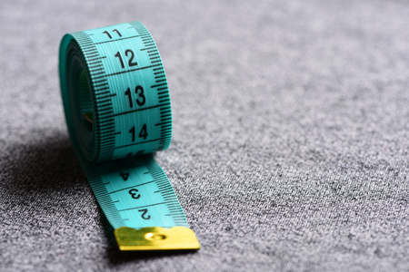 Tape for measuring of cyan color on light grey background in close up, selective focus and copy space. Minimalistic concept of accuracy and precisionの写真素材