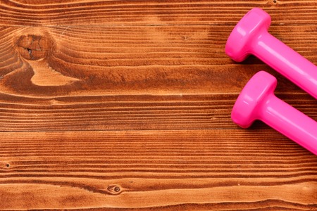 training concept, pink dumbbells on brown vintage wooden background, copy spaceの写真素材