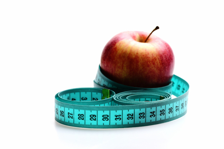 Concept of weight management, healthy nutrition and vitamin diet: red apple wrapped by cyan measuring tape, isolated on white background, selective focusの写真素材