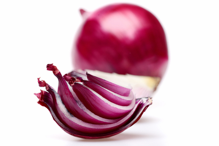 Sliced red onion quarter in close up and whole purple vegetable behind it isolated on white background, selective focus. Beauty in foodの写真素材