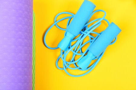 Sports for health. Skipping rope isolated on yellow background and purple yoga mat presenting concept of healthy lifestyle and athletic shape. Top viewの写真素材