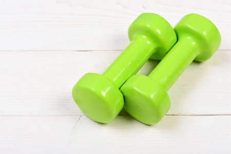 green dumbbells on white vintage wooden background with exercise conceptの写真素材