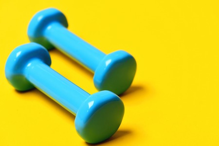 barbell or dumbbells on yellow background, fitness concept