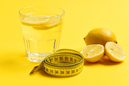 meter tape, lemon with freshly squeezed glass of citrus on yellow background. Nutrition and diet conceptの写真素材
