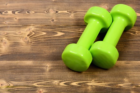 objects and healthy lifestyle concept, green dumbbells on brown vintage wooden backgroundの写真素材