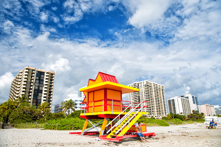 Miami, USA - January 10, 2016: Miami beach or south beach colorful lifeguard tower, wooden station, on sandy beach, green palms, high rise buildings on sunny cloudy blue sky. Summer vacation. Safetyのeditorial素材