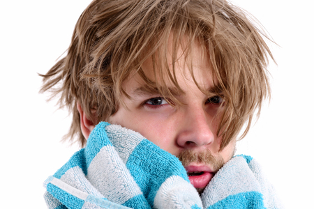 Man with tired and sleepy face expression and messy hair towels his chin, isolated on white background, close up. Morning shower time conceptの写真素材