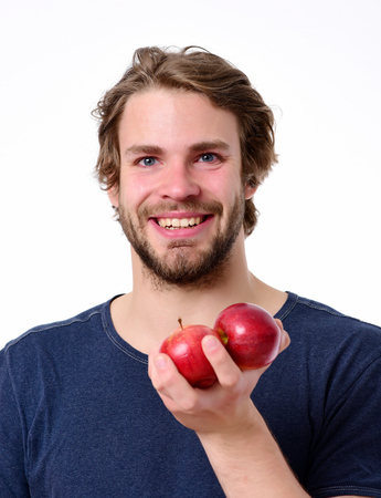Smile and fruit. Happy caucasian man in dark blue tshirt holding pair of red apples in hand. Isolated on white background, portraitの写真素材