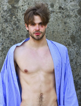 Bearded man, short beard. Caucasian macho with moustache and ruffled hair in blue striped pajamas...