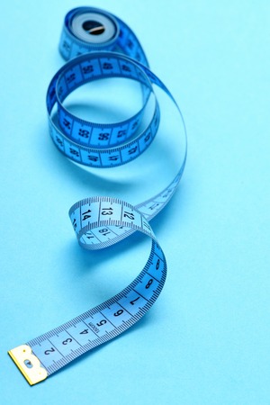 Roll of untwisted tape for measuring isolated on light blue background. Minimalistic concept of metering and diet, selective focusの写真素材
