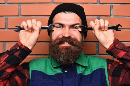 Bearded man, long beard. Brutal caucasian smiling happy mechanic, unshaven hipster in black hat,...