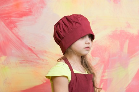 Cooking, food, study. Small girl in chef hat on colorful background