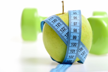Apple and blue flexible ruler on white background and dumbbell on behind, selective focus. Health and fitness conceptの写真素材