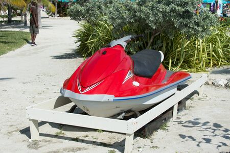 water craft, scooter or jet ski boat, red color motor vessel, parked on ground on sunny day on...