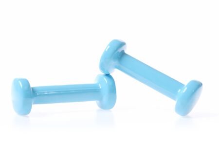 Two dumbbells in light cyan colour leaning on one another, isolated on white background, close up. Concept of sports and healthの写真素材