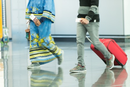 People with bags and suitcases in airport or station. Female and male legs in sport shoes walking on grey tile floor. Hands holding passports and tickets. Travel and traveling. Vacation and adventureの写真素材